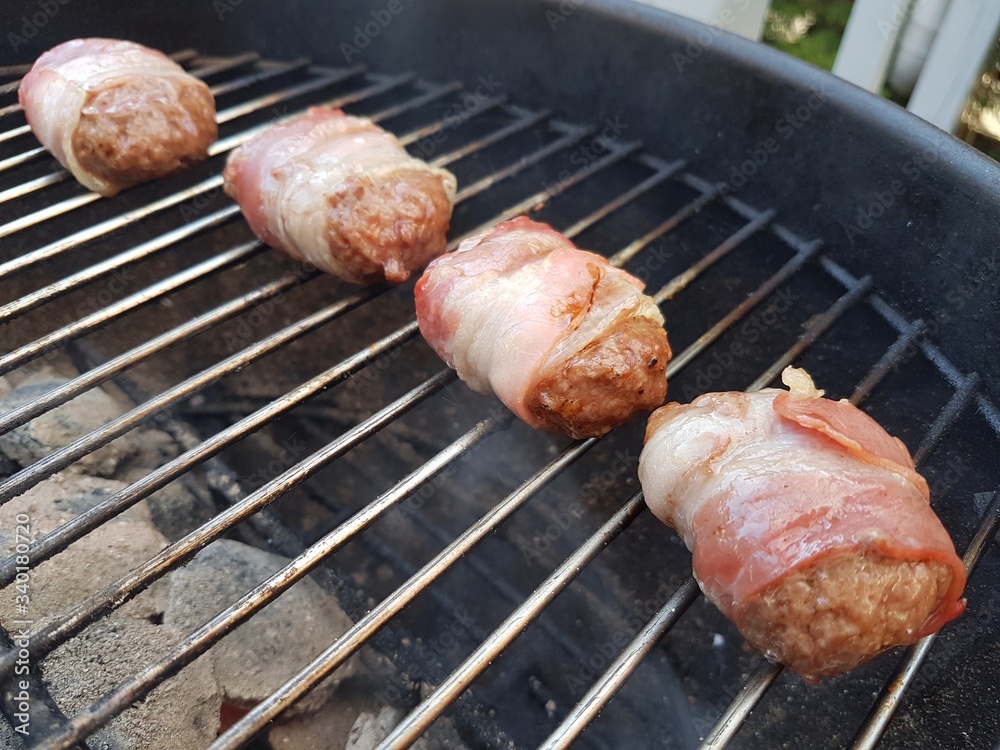 Ground beef wrapped in bacon cooked on barbecue grill