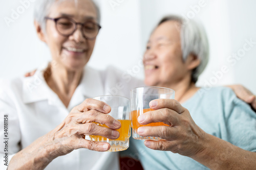 Healthy elderly sibling drinking vitamin C,orange juice and clinking glasses at home,senior people with effervescent vitamin C,strengthening the immunity for cold,flu,prevent the Covid-19,health care