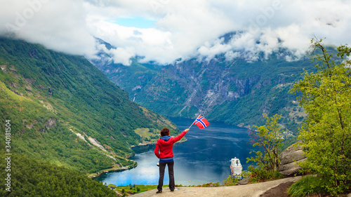 Tourist over Geirangerfjord holds norwegian flag photo