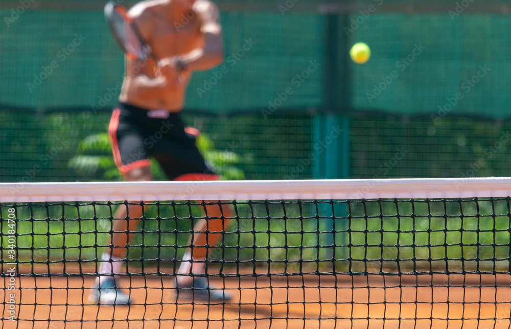 A man plays tennis on the court in the park.