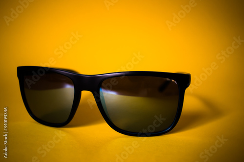 Close up of black sunglasses on yellow background