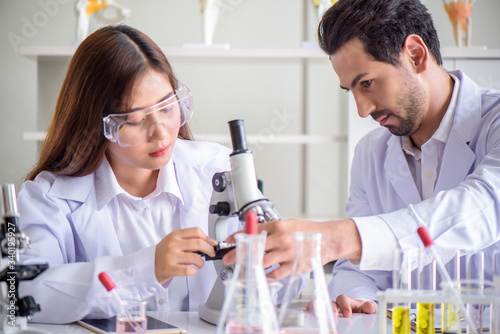 Attractive happiness scientist lab technician assistant analyzing sample in test tube at laboratory. Medical  pharmaceutical and scientific research and development concept.