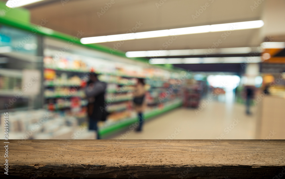 Obraz premium Supermarket background, Counter over blur grocery background, Wooden desk, table, shelf and blur woman shopping at supermarket, Wood counter for grocery store retail product display backdrop, template