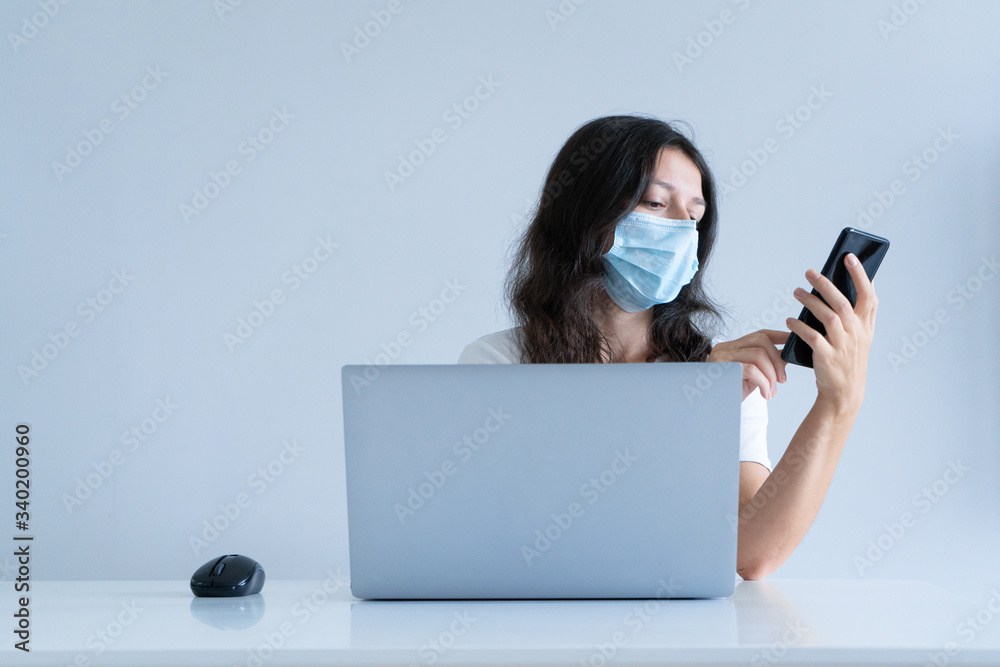 The girl works from home during quarantine. Corona virus pandemic. A girl in a surgical mask works on a laptop and drinks coffee. Distant work The girl works from home during quarantine. Corona virus pandemic. A girl in a surgical mask works on a laptop and drinks coffee. Distant work
