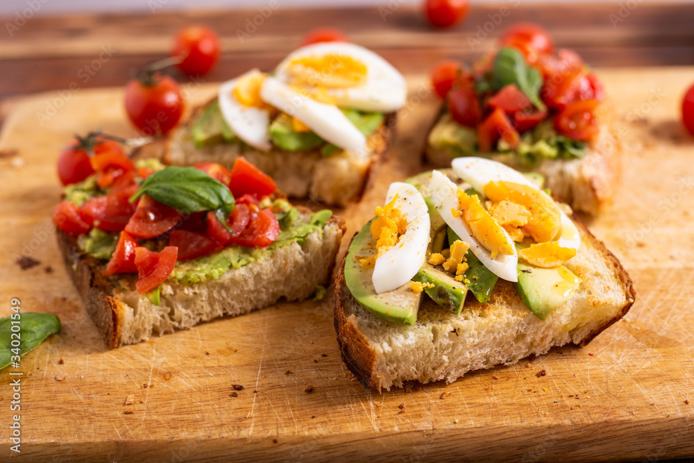 Mixed avocado toast with boiled eggs and tomatoes. Ideas for fast and nutritious dish. Summer food.