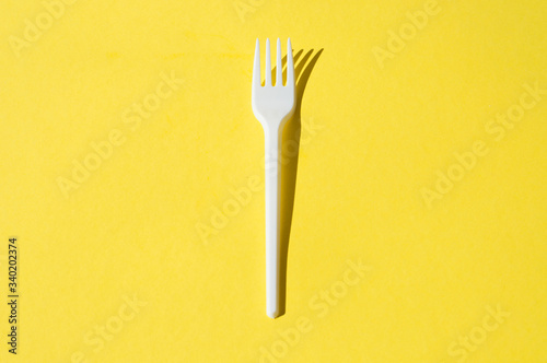 White plastic fork on a yellow background