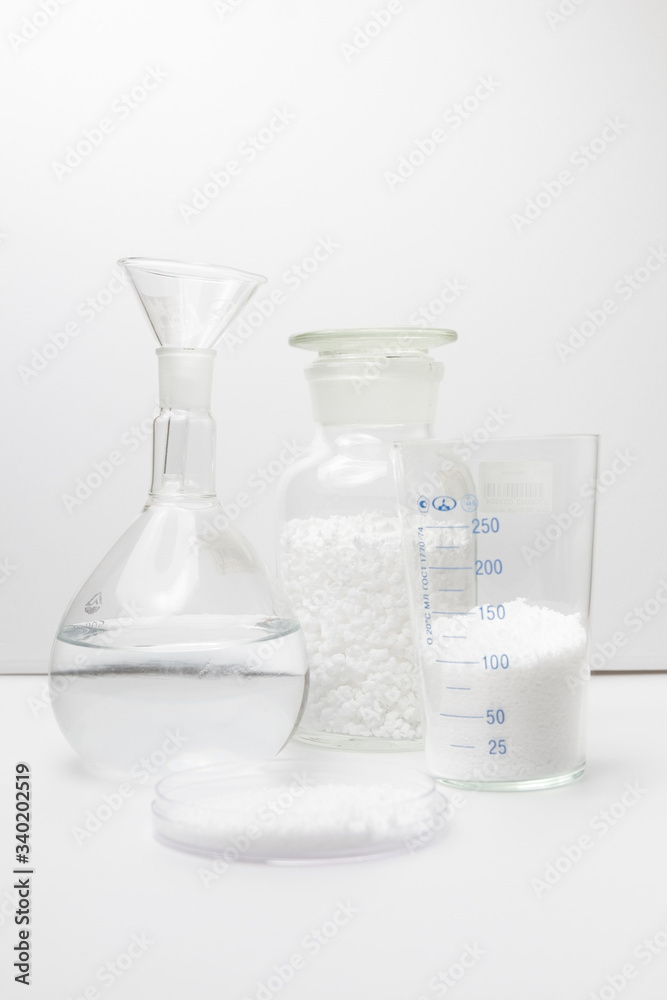 glass laboratory jar with samples of white synthetic rubber on a white background glass laboratory jar with samples of white synthetic rubber on a white background