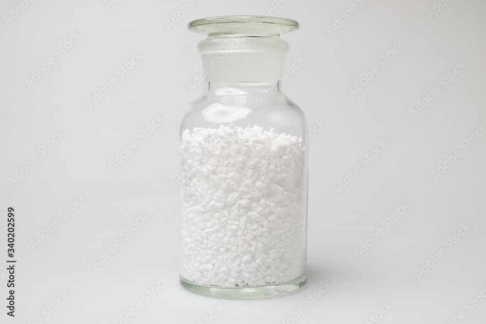 glass laboratory jar with samples of white synthetic rubber on a white background glass laboratory jar with samples of white synthetic rubber on a white background
