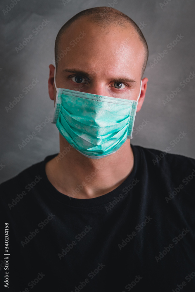 Portrait of young man wearing a medical protection mask from coronavirus with gray background Portrait of young man wearing a medical protection mask from coronavirus with gray background