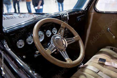  Interior View of Restored 50s Vintage Automobile Dashboard Steering Wheel, Out of Focus People in Background  © Jacquie Klose