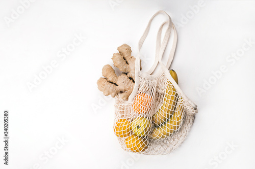Package-free food shopping. Reusable string shopping bag with banana, orange, apple, lemon and ginger. Zero waste concept.