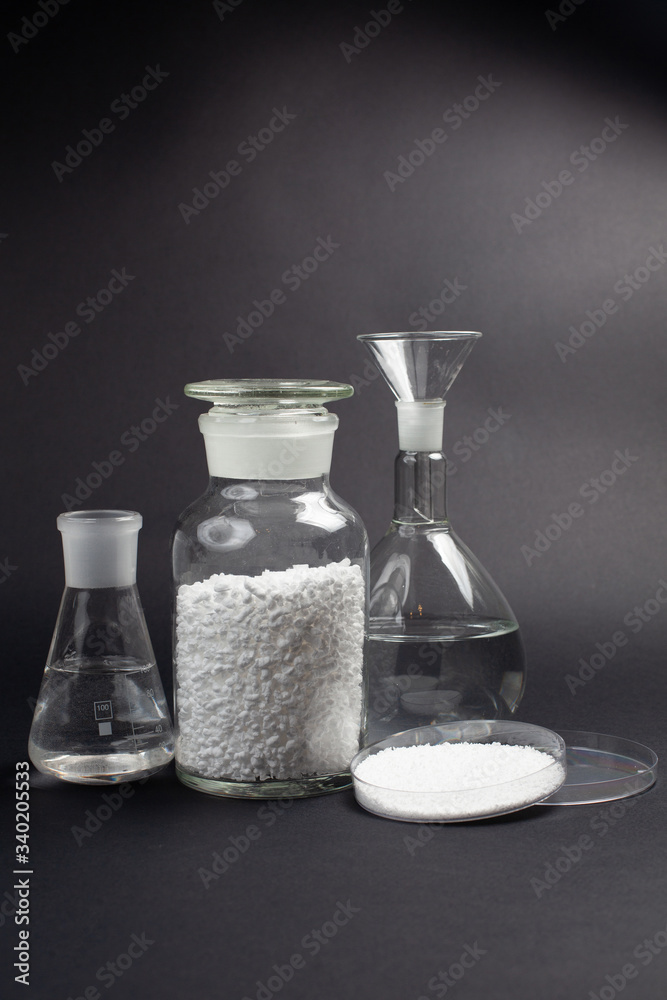 glass laboratory jar with samples of white synthetic rubber on a black background glass laboratory jar with samples of white synthetic rubber on a black background