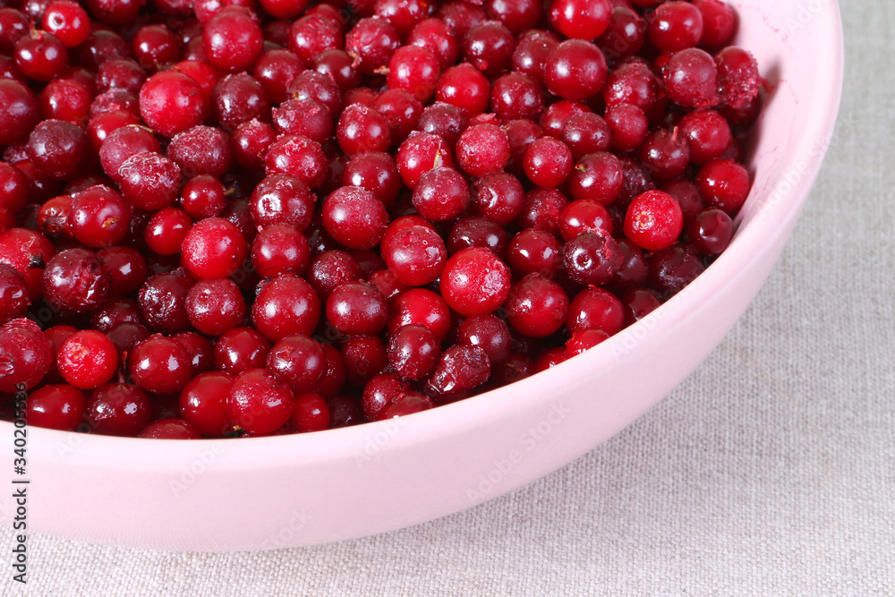 Frozen cranberry in pink plate on linen tablecloth