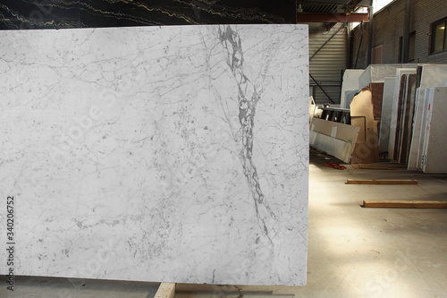 A slab of natural white marble with gray veins in a stone warehouse is called Bianco Gioia