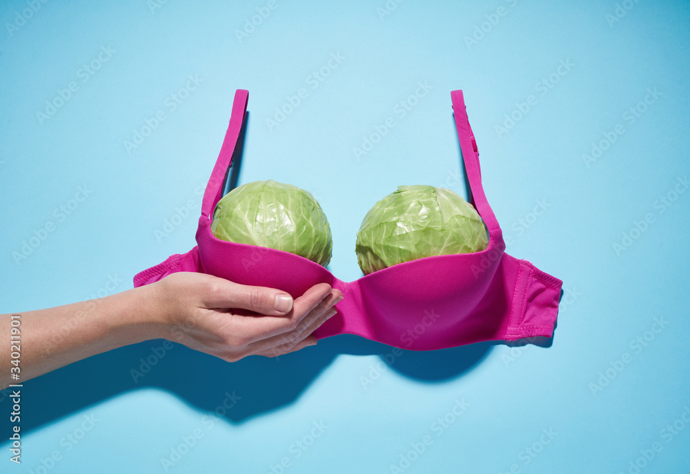 Two large cabbage in a pink bra, imitation of a large female breast. - obrazy, fototapety, plakaty 