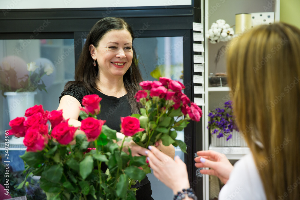 seller in the flower shop sells a bouquet of flowers to the buyer