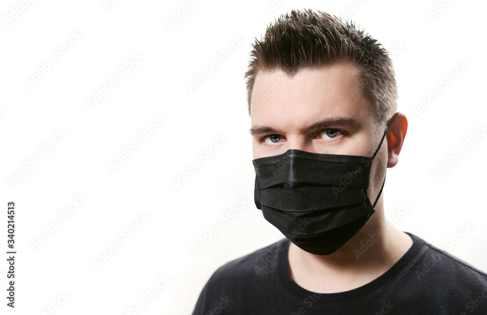 Closeup frowning man in disposable medical mask isolated on a white background. Covid-19 coronavirus epidemic. Quarantine and self-isolation mode to save the population. Closeup frowning man in disposable medical mask isolated on a white background. Covid-19 coronavirus epidemic. Quarantine and self-isolation mode to save the population.
