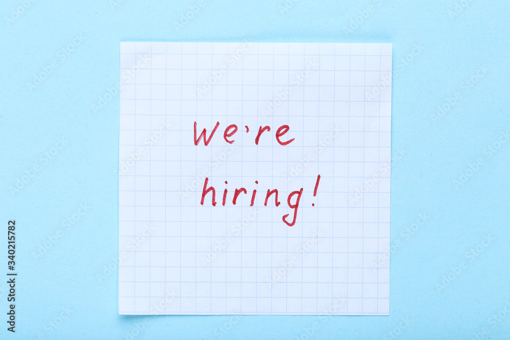 Text We Are Hiring on paper on blue background