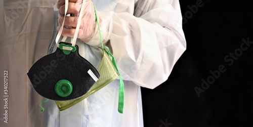 The gloved hand of a worker wearing a waterproof suit holds a mask and splash goggles just removed. Biohazard protection elements photo