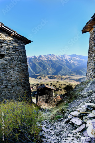 A pathway crosses the the ancient fort's  towers in the village of Upper Omalo in Tusheti with mountains in the background photo