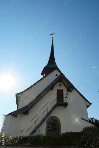 Old reformed church building in Urdorf, lateral view on a clear day with blue sky, the photo taken in upward perspective.