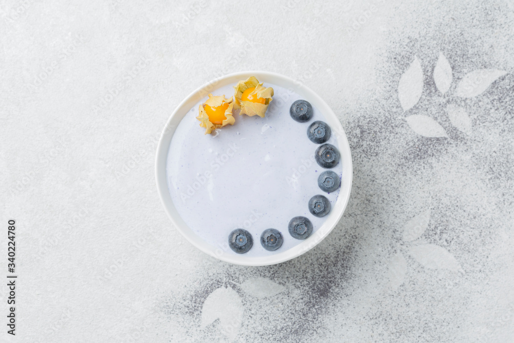 Healthy Breakfast smoothie bowl with coconut yogurt, blue matcha tea, blueberries and physalis. Top view Healthy Breakfast smoothie bowl with coconut yogurt, blue matcha tea, blueberries and physalis. Top view