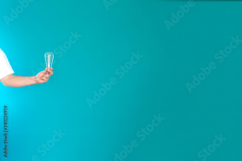 Left hand holding a light bulb on a green background