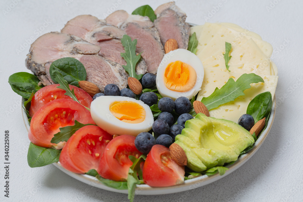 Ketogenic diet. Bowl with meat, avocado, eggs, berries, tomatoes, cheese and nuts. Detox and healthy concept. Keto food. 