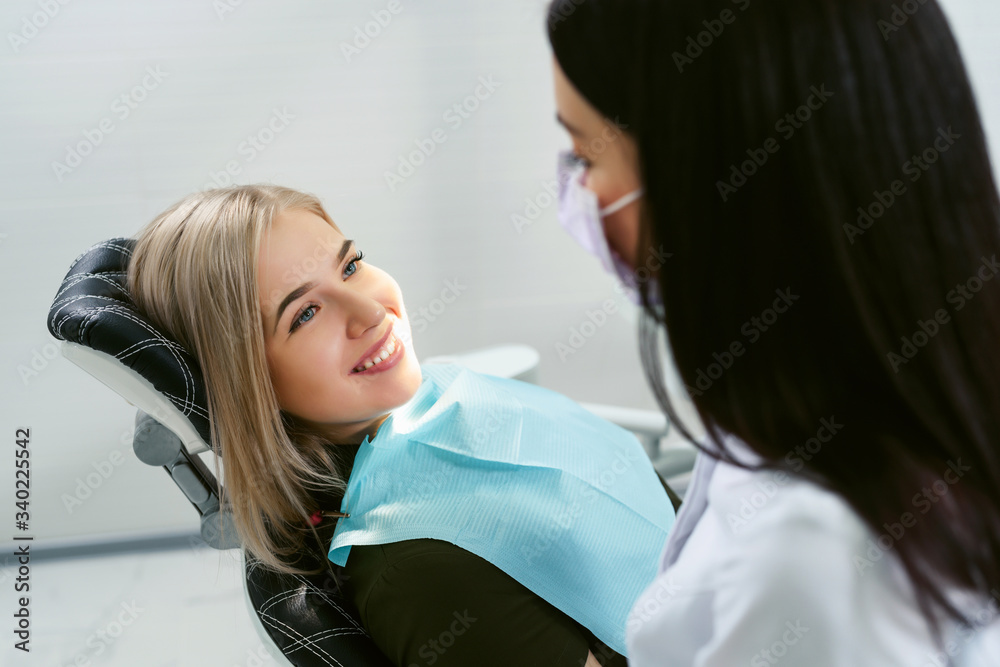 Dentist examining a patient's teeth in modern dentistry office. Closeup cropped picture with copyspace. Doctor in disposable medical facial mask.