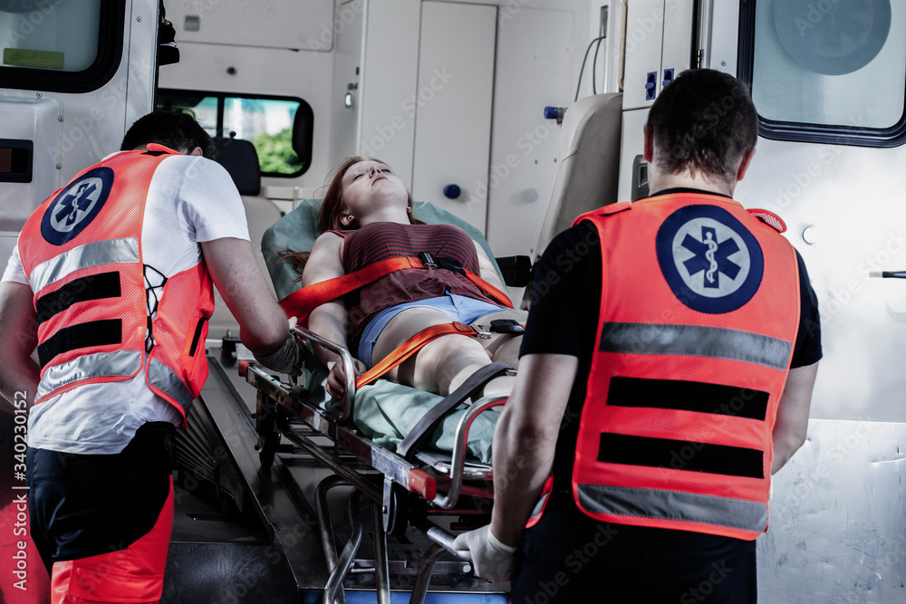 Female young victim of the accident lies on a stretcher in an ambulance ...