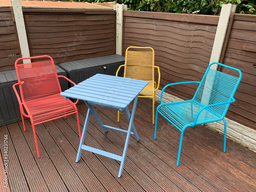 A bright coloured outdoor bistro garden table and chairs on some worn decking