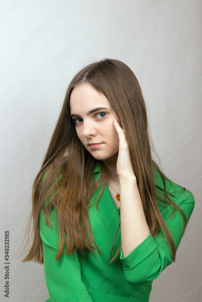 close-up portrait of a blonde long-haired romantic girl with big gray blond eyes in a green dress