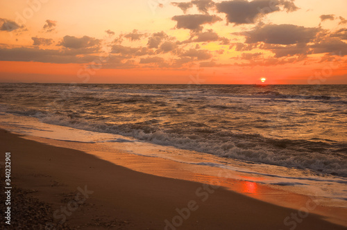 Natural background for text and sand and sea waves. Footprints in the sand from the legs go into the distance. Summer, sea, sunrise. © Nelly