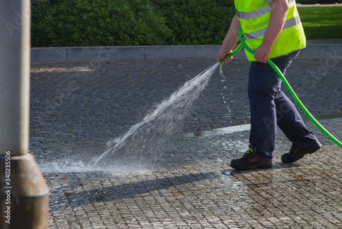 Worker washing sidewalk.