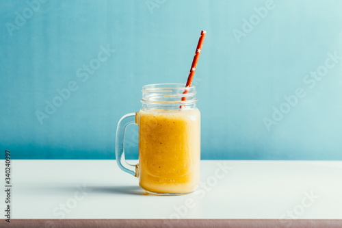 tasty mango smoothie in a glass jar on a blue background