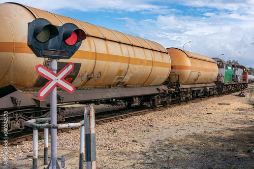 Fotografie Traffic signal level crossing warning lights, tank cars for transporting dangerous gases circulating on the track