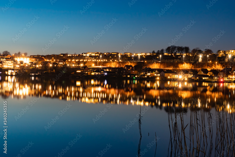 Fototapeta premium A beutiful water reflection of the city of Skanderborg in Denmark by night at a lake