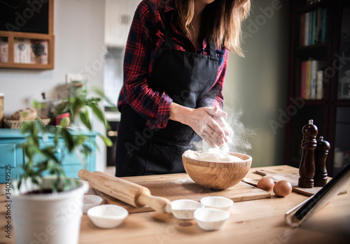Obraz na plátně Woman cooking pastries and bread at home looking for recipes on tablet