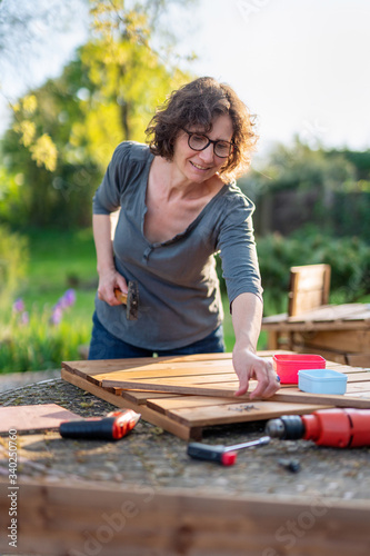 Portrait of a middle-age woman, she is building wooden planters for vegetable garden