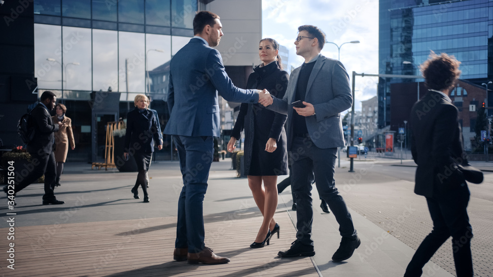 Multicultural Diverse Office Managers and Business People Walking on a Street. Female and Male Meet a Corporate Partner next to Business Center and Shake Hands. Multicultural Diverse Office Managers and Business People Walking on a Street. Female and Male Meet a Corporate Partner next to Business Center and Shake Hands.