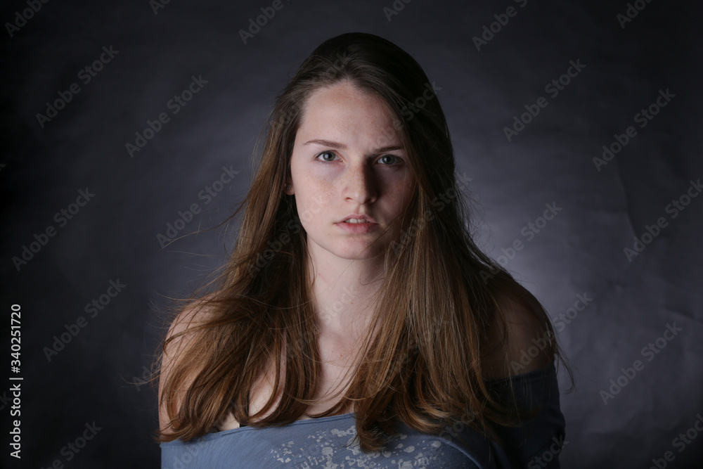 Studio portrait of young girl with light hair and freckles, with dark background. Studio portrait of young girl with light hair and freckles, with dark background.