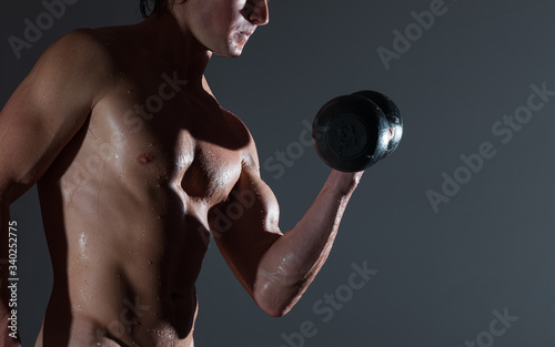 Young bodybuilder with naturally looking and wet body (body has hairs and birthmarks) holds dumbbell © Dudarev Mikhail