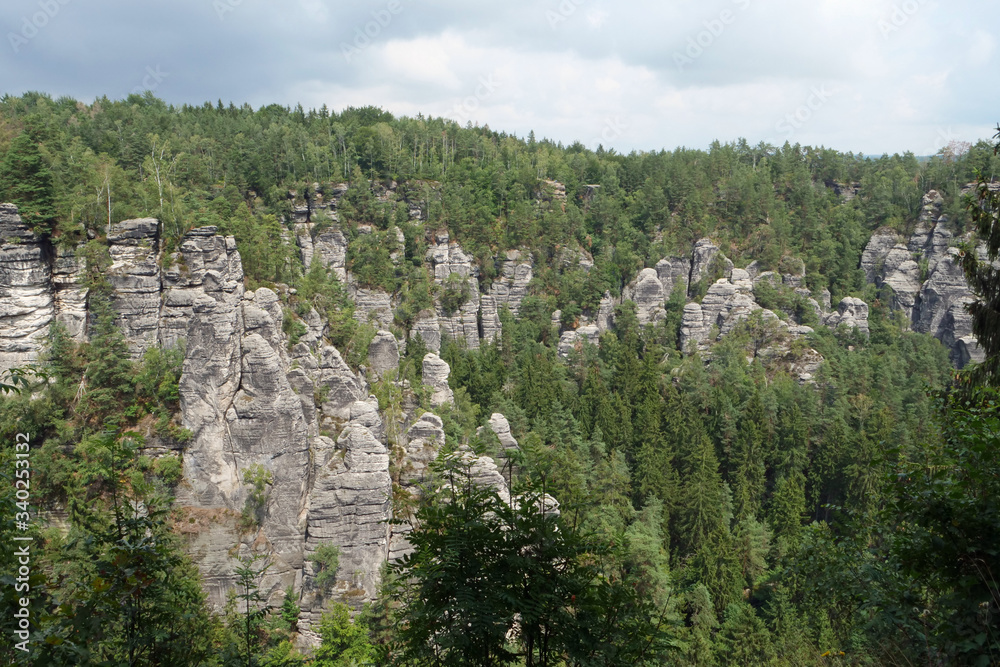 Huge black grey colored and fissured sandstone rocks surrounded by forest; Saxon Switzerland, Germany, Europe
