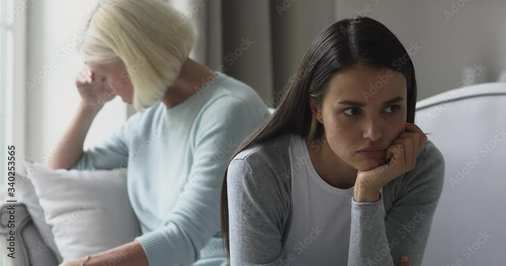 Head shot depressed two generations women sitting back to back, ignoring each other after fight. Depressed middle aged mother and young selfish stubborn grownup daughter feeling stressed after argue. Head shot depressed two generations women sitting back to back, ignoring each other after fight. Depressed middle aged mother and young selfish stubborn grownup daughter feeling stressed after argue.
