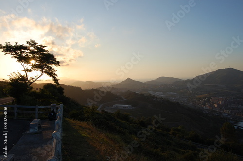 Atardecer en la montaña en el País Vasco, la puesta de sol de cuela  a través de las ramas de un árbol solitario photo