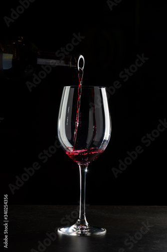 Rose wine pouring in a glass on black background