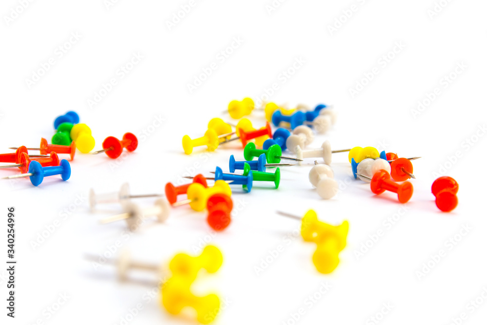 Multi-colored pushpins scattered over a white-grey background. Multi-colored pushpins scattered over a white-grey background.