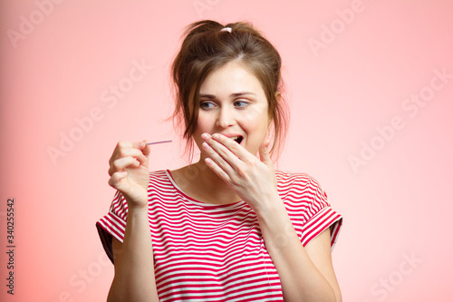 young happy woman with positive result result of pregnancy test, girl excited about good news, family planning, motherhood concept on pink studio background