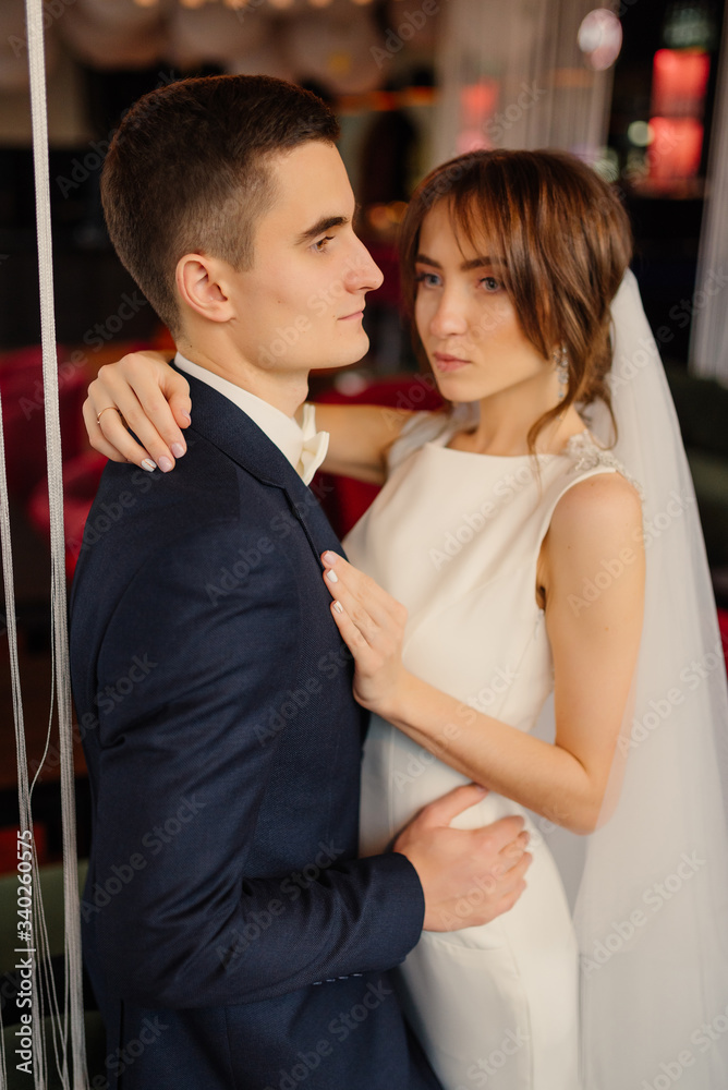 Obraz premium Elegant newlyweds at a photo shoot in a modern interior. Wedding, love, relationship concept.