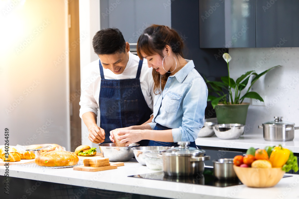 Beautiful young Asian couple preparing a healthy meal together at home. Romantic couple cooking together on kitchen.